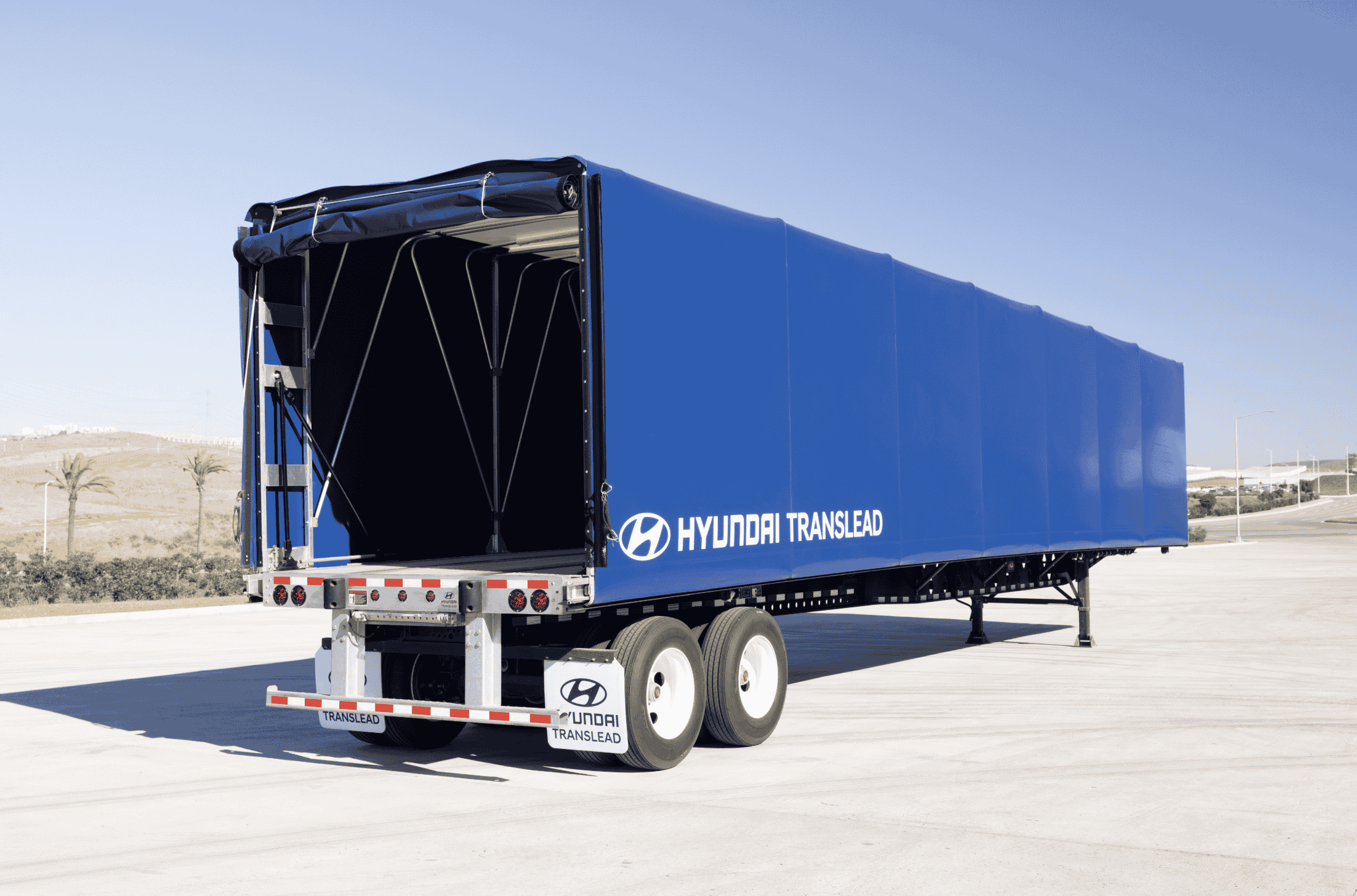 A blue Hyundai Translead Latitude flatbed trailer with a retractable tarp system, showcasing Hyundai's innovation and trailer technology for versatile cargo transport.